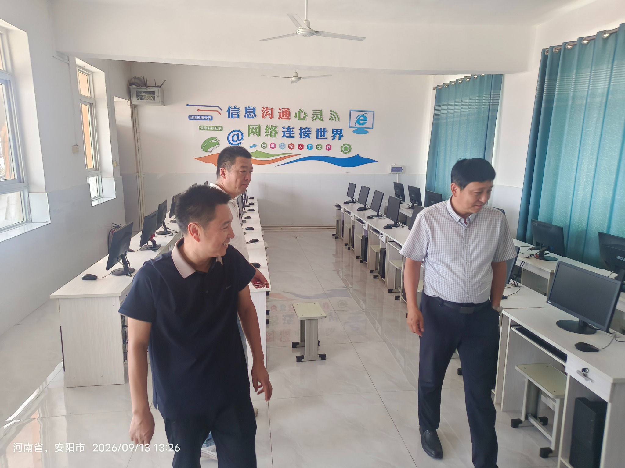 午后参观时,三位老师在摆放整齐的微机室里查看