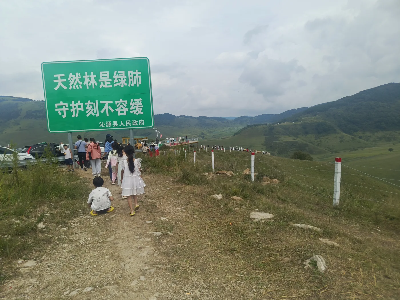 孩子站在生态提示牌和远山之间