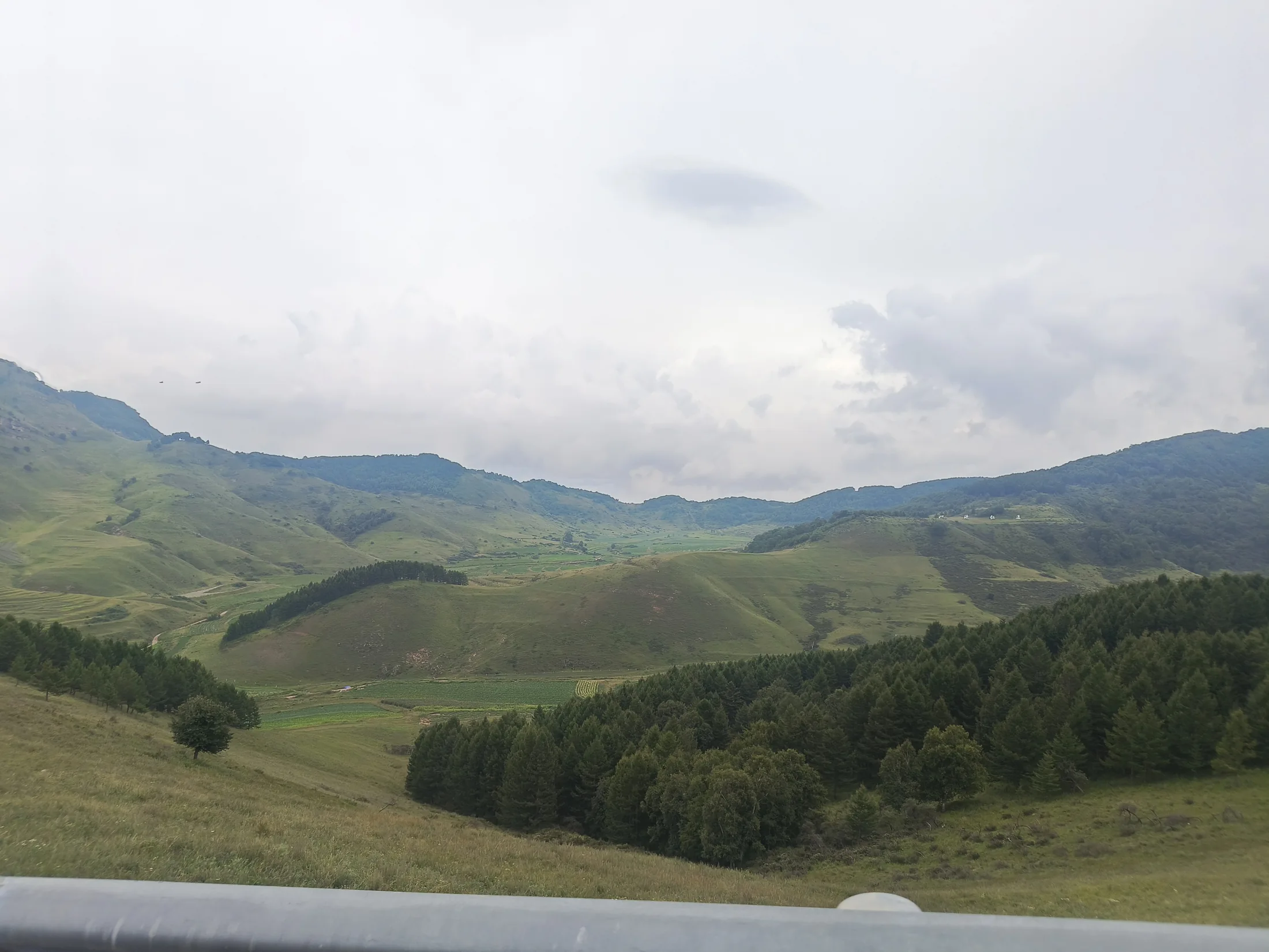 低云下层层展开的绿色山谷与林地