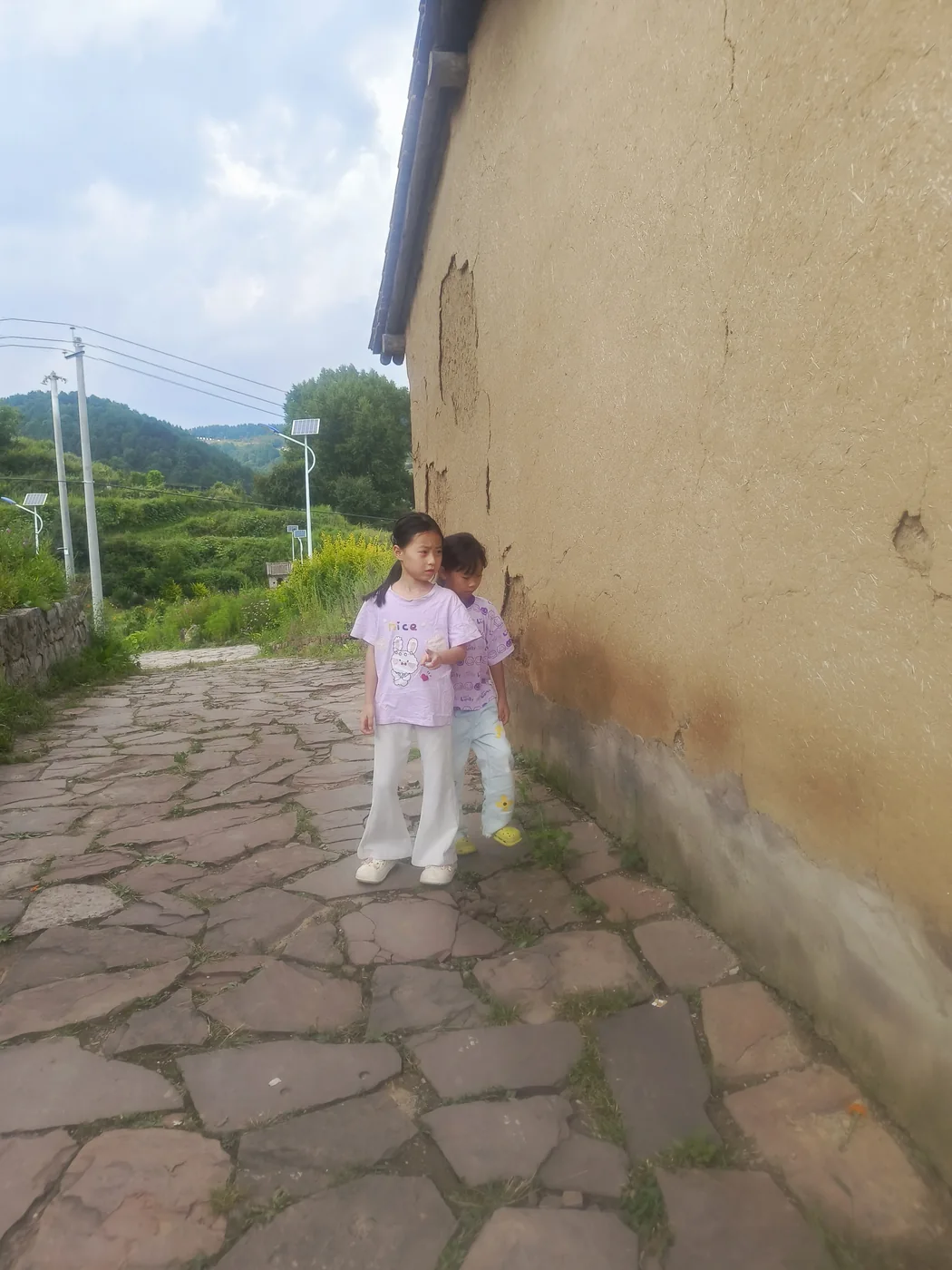 孩子走过山村的土墙与石板路