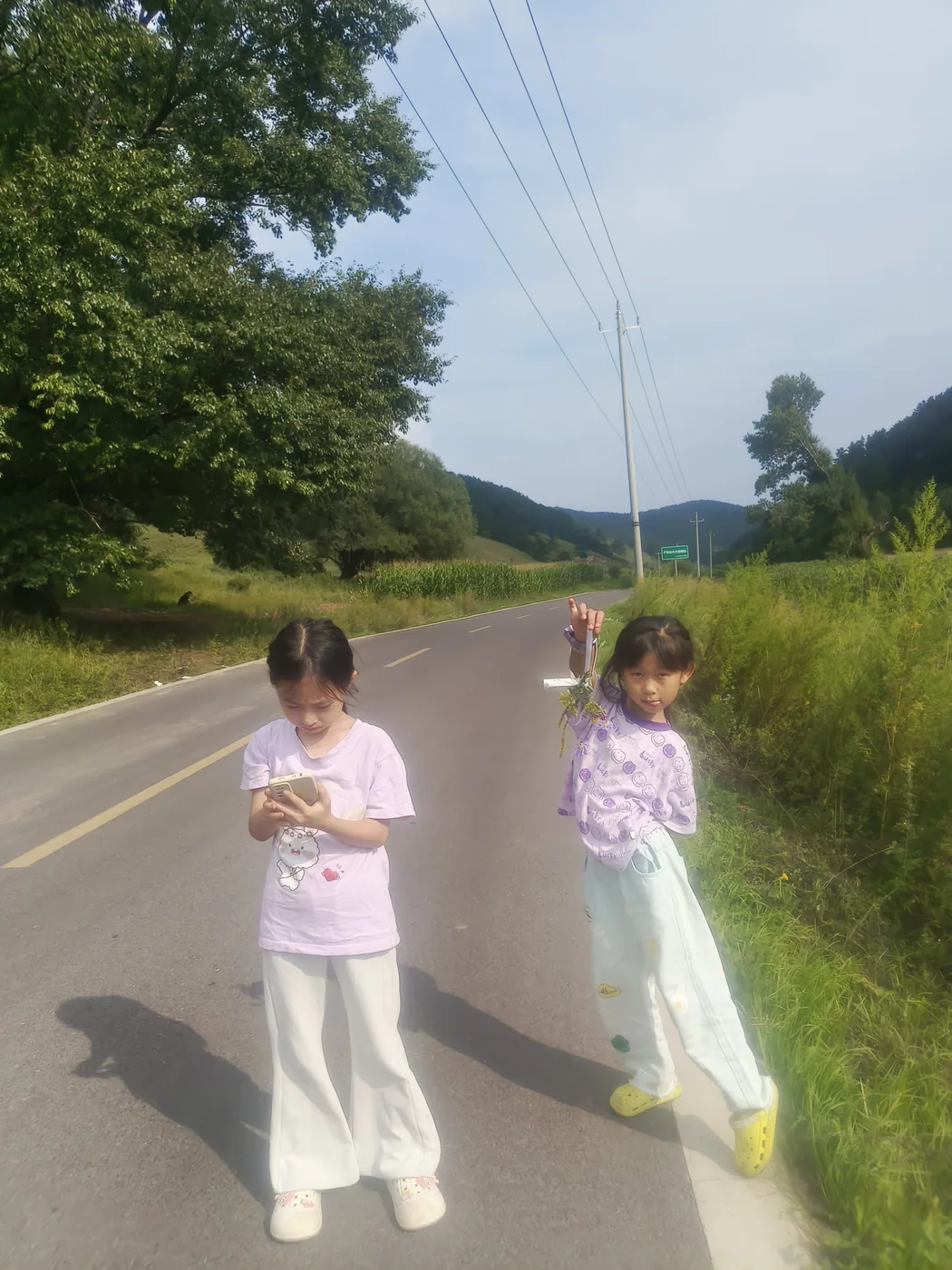 两个孩子在山路旁近距离说笑互动