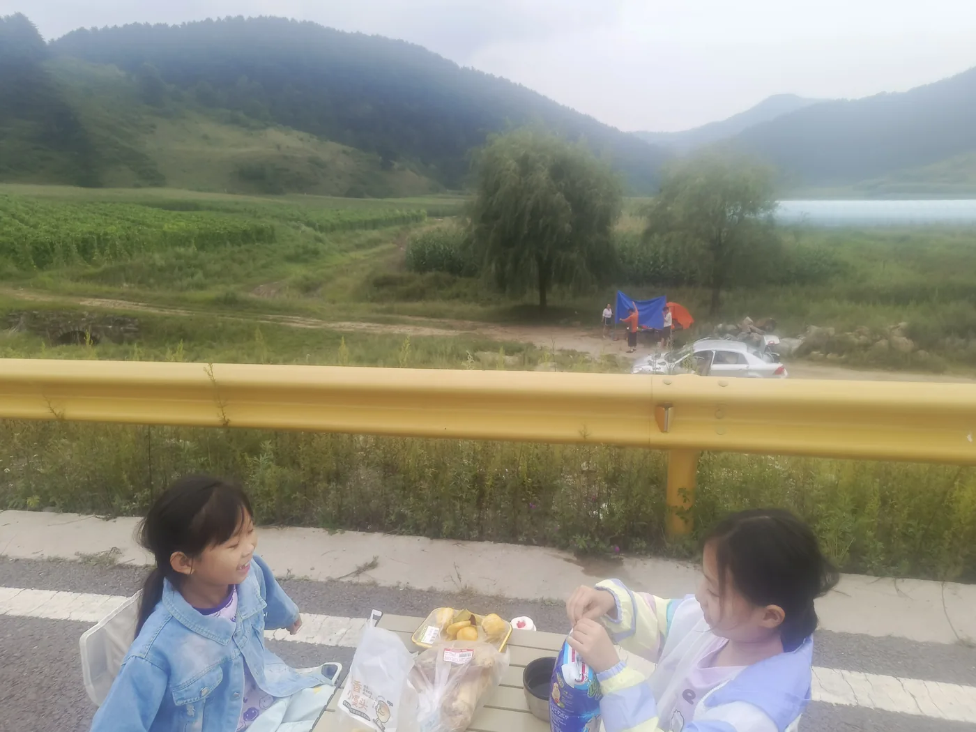 家人在山边摆开桌椅分享食物
