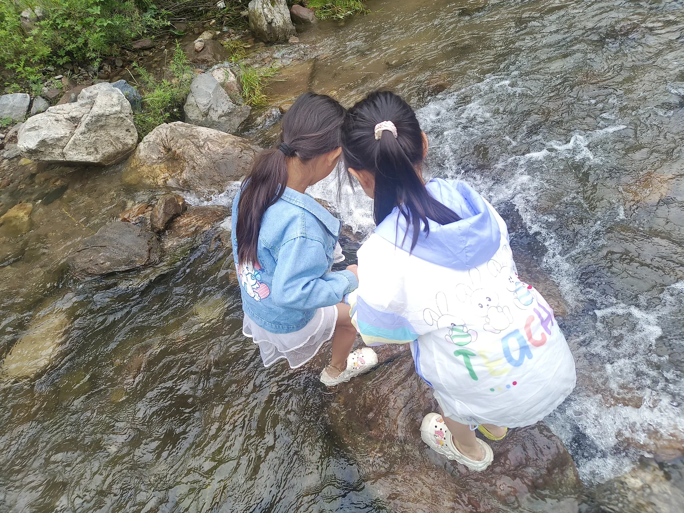 两个孩子在溪水中近距离互相扶助