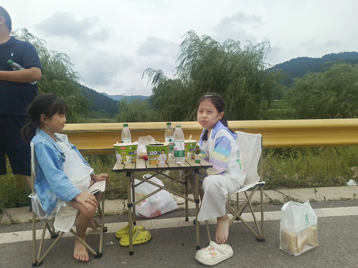 两个孩子坐在户外餐桌旁休息