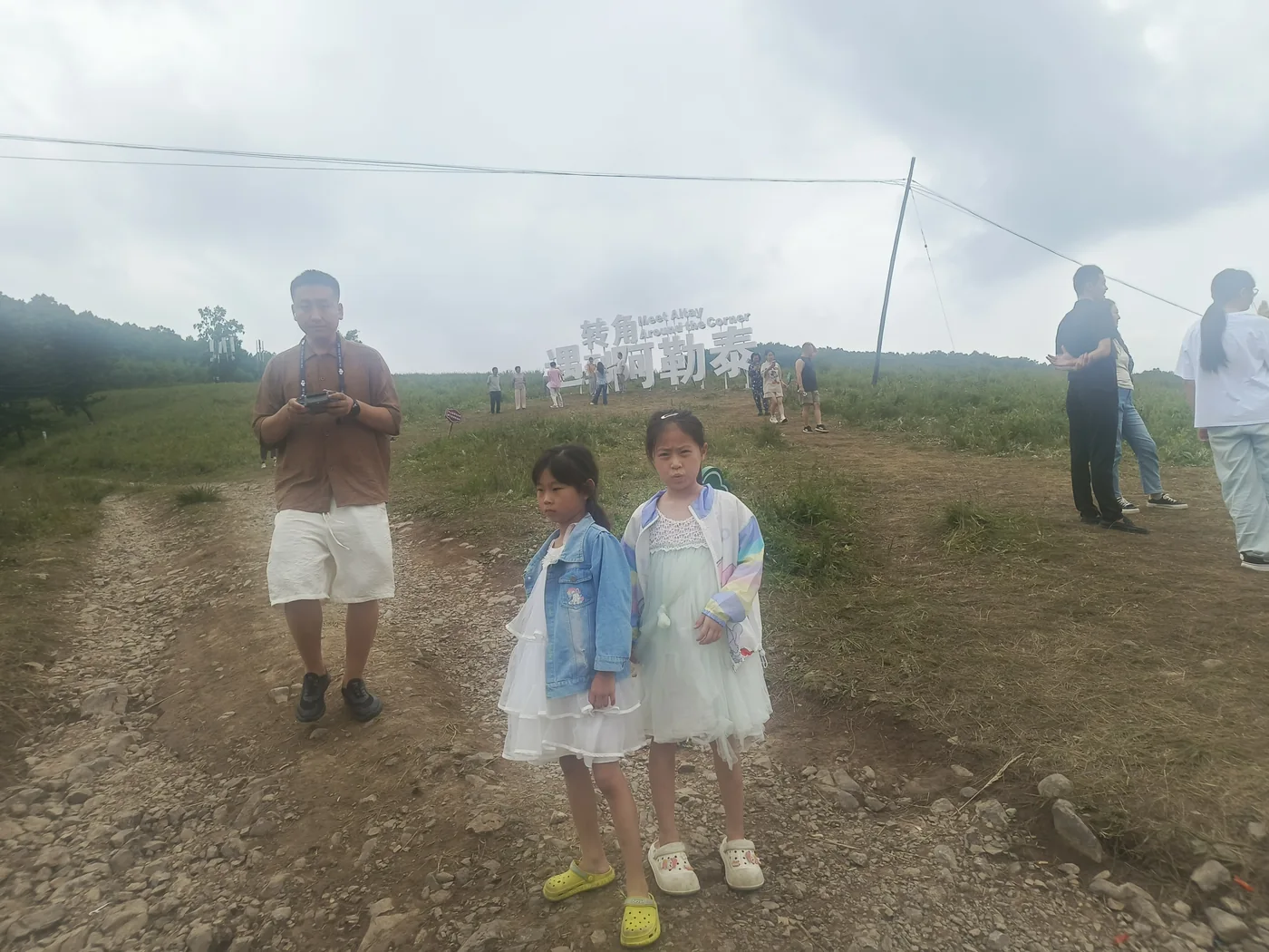 两个孩子站在开阔草地与远山之间
