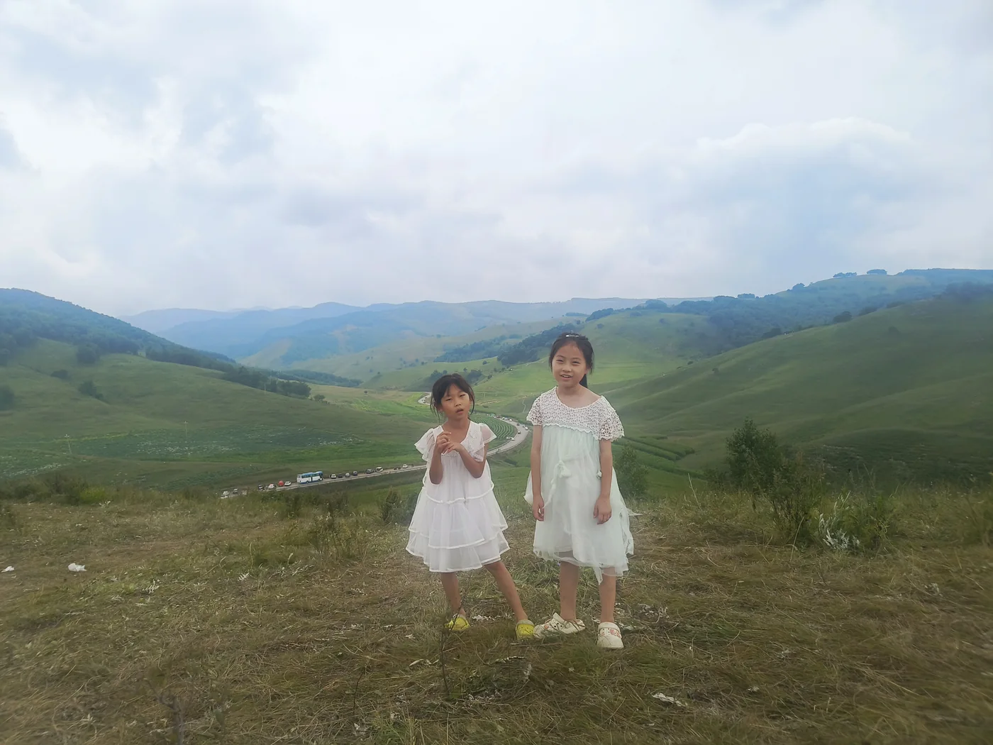 两个孩子在高山草甸与群山前合影